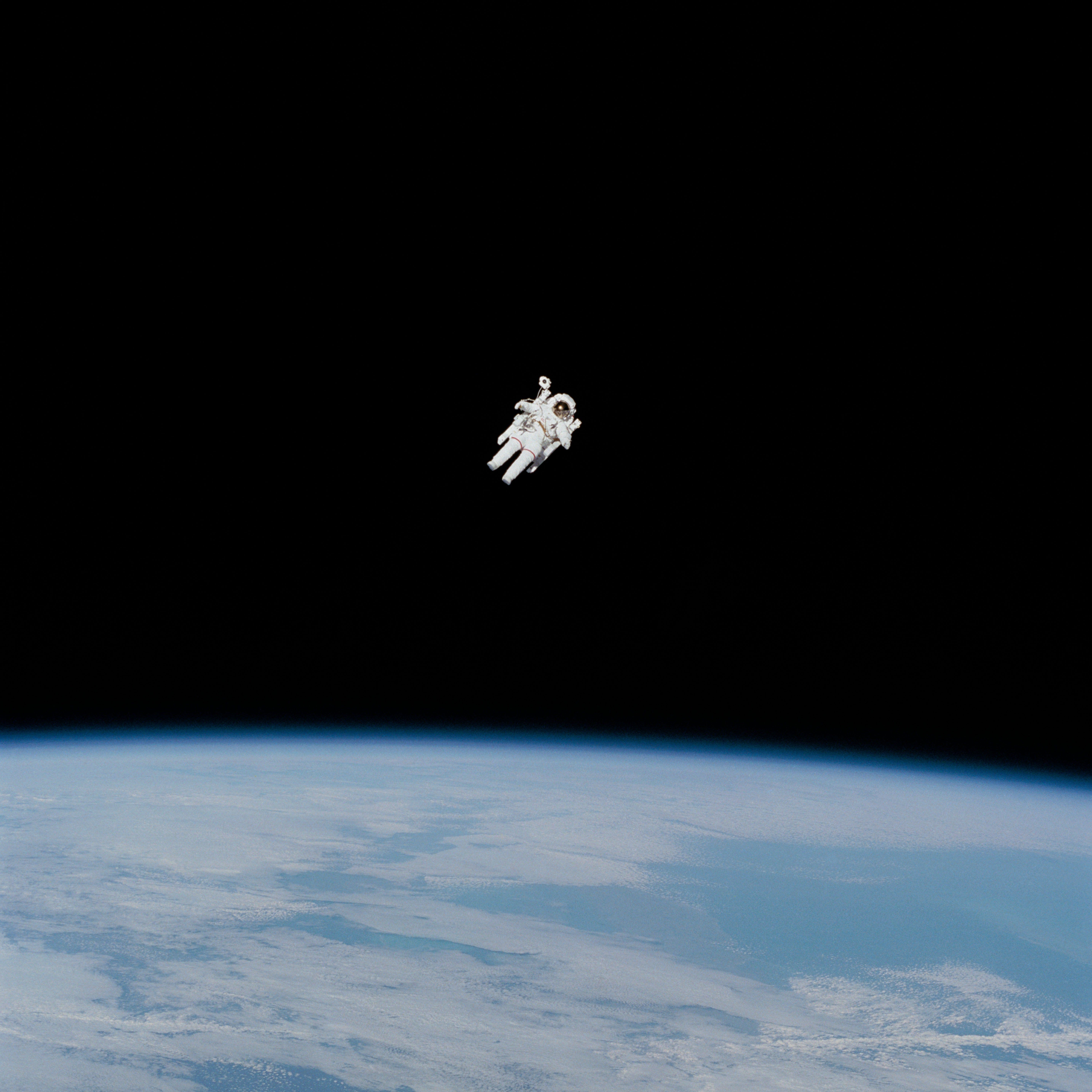 An astronaut floating in space above the Earth. - Space