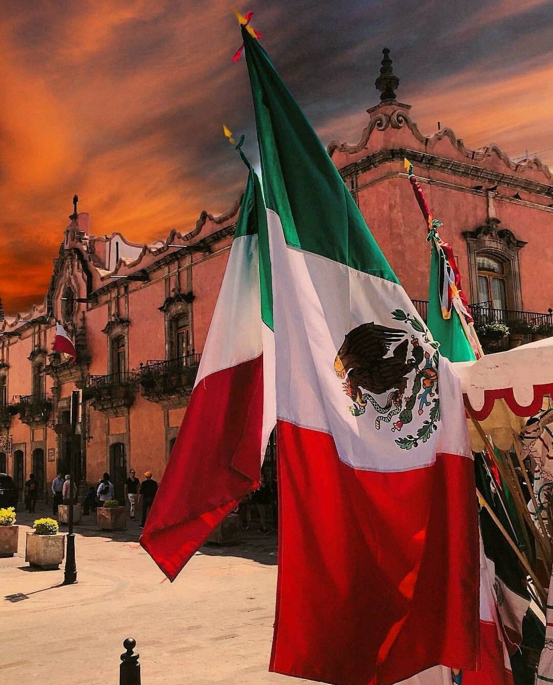 A mexican flag is flying in front of an old building - Mexico