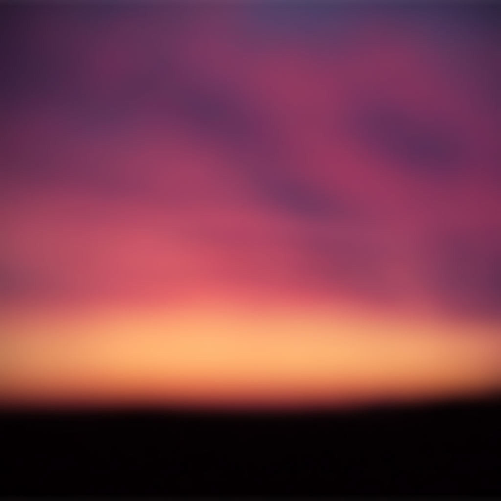 A sunset with a purple, orange, and pink gradient - Blurry