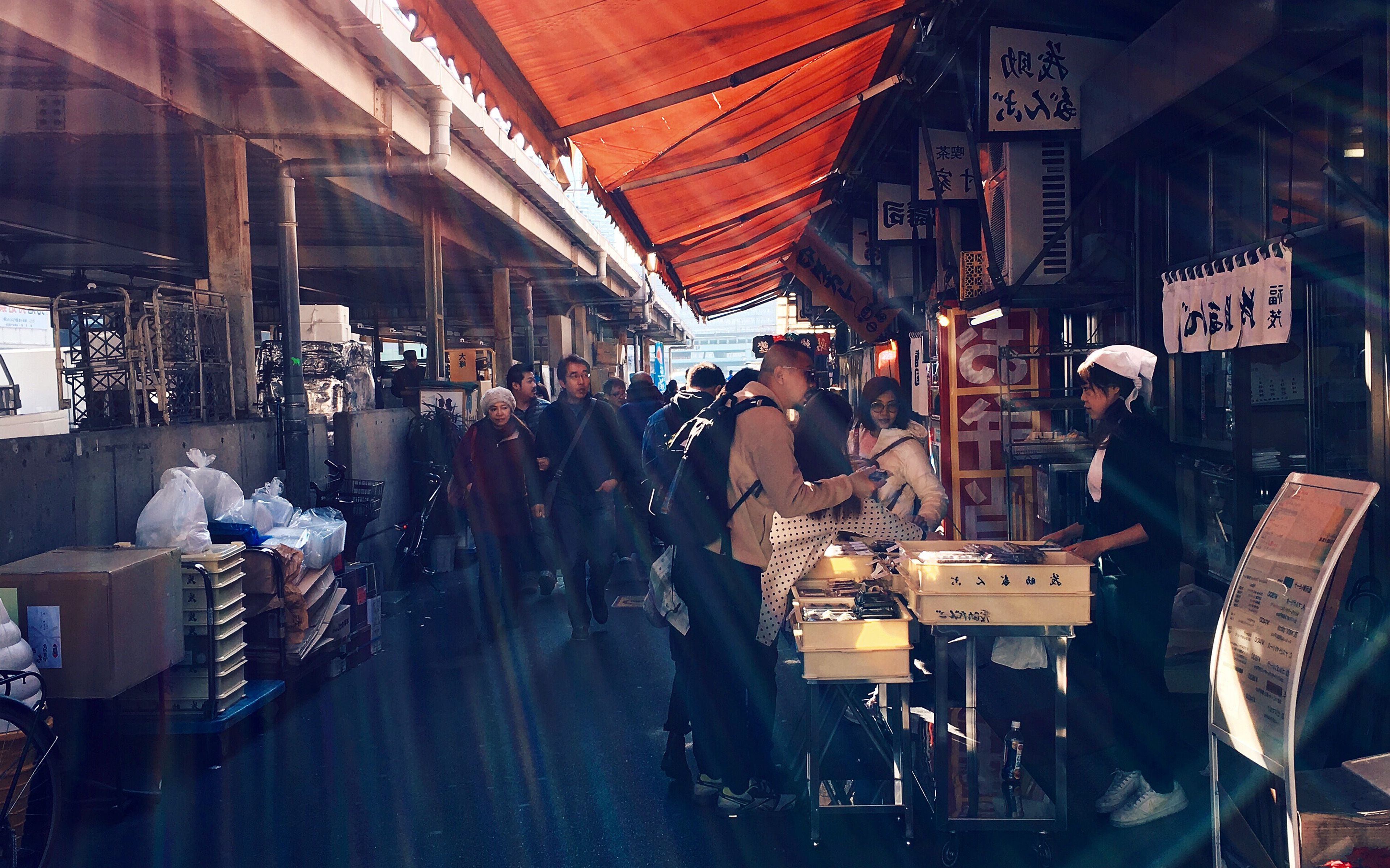 A group of people standing around a market. - Travel