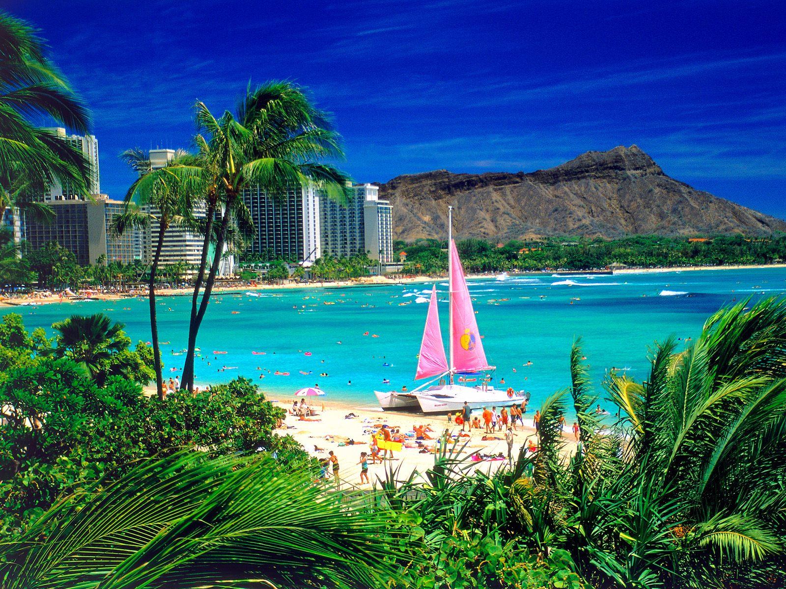 A beach with people and sailboats in the water - Hawaii