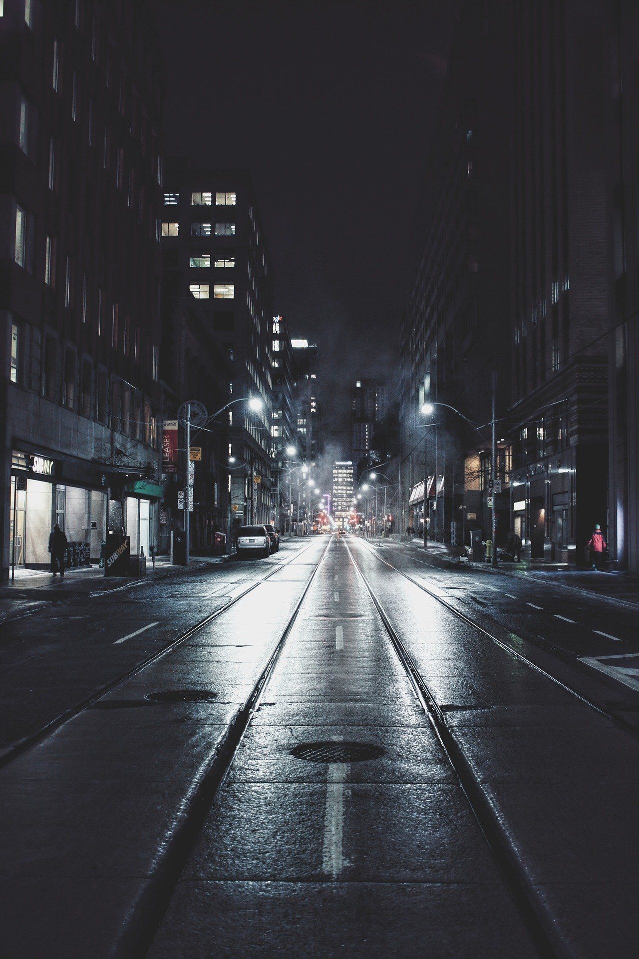 A dark street at night with street lights illuminating the road - Dark