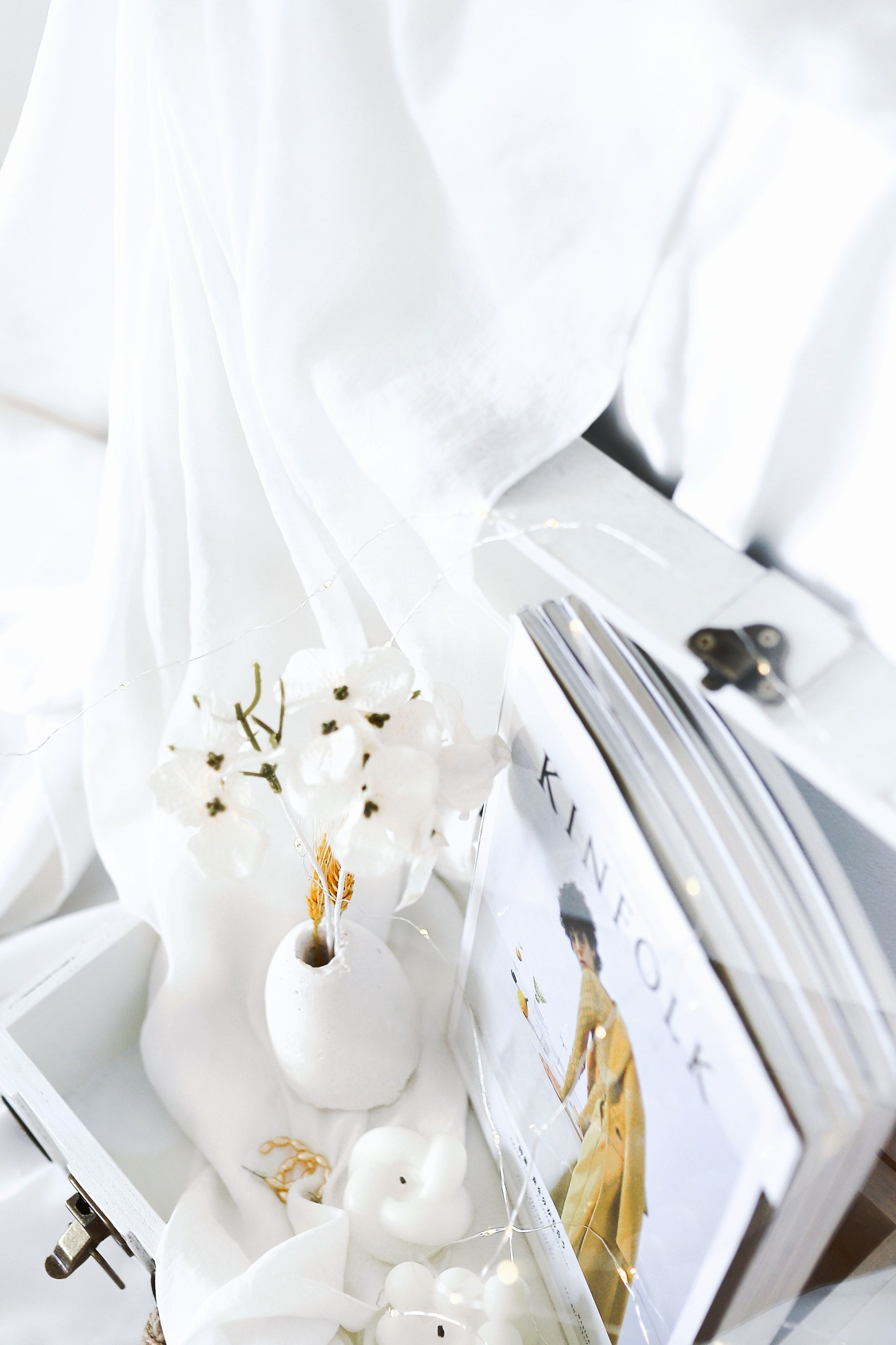 A box of white candles, flowers, and magazines. - White, cute white