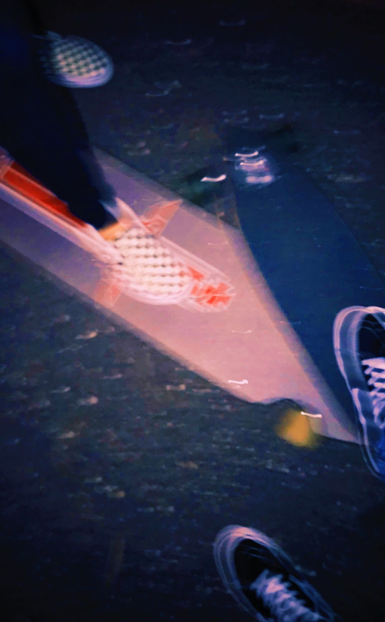 A skateboard and a person's feet wearing sneakers are reflected in a puddle. - Skate, skater