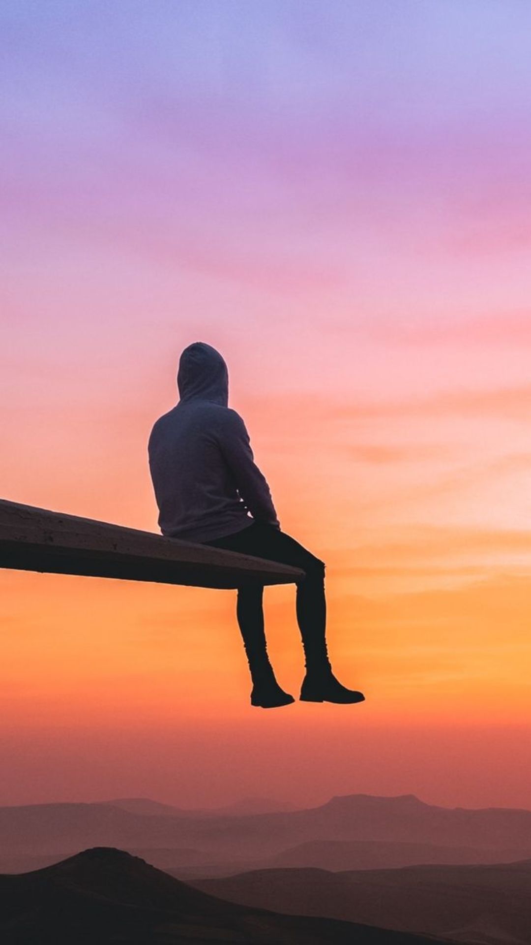 A person sitting on a ledge watching the sunset - Calming