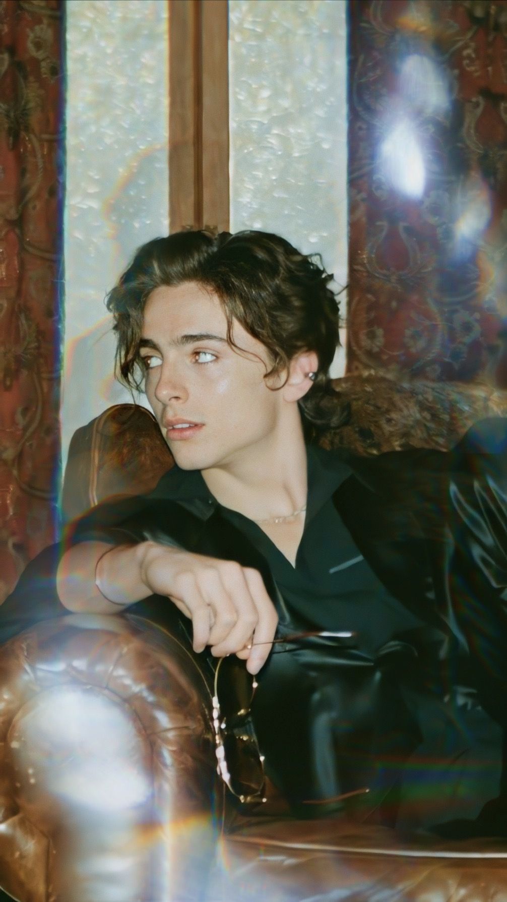A man in black sitting on top of some leather - Timothee Chalamet