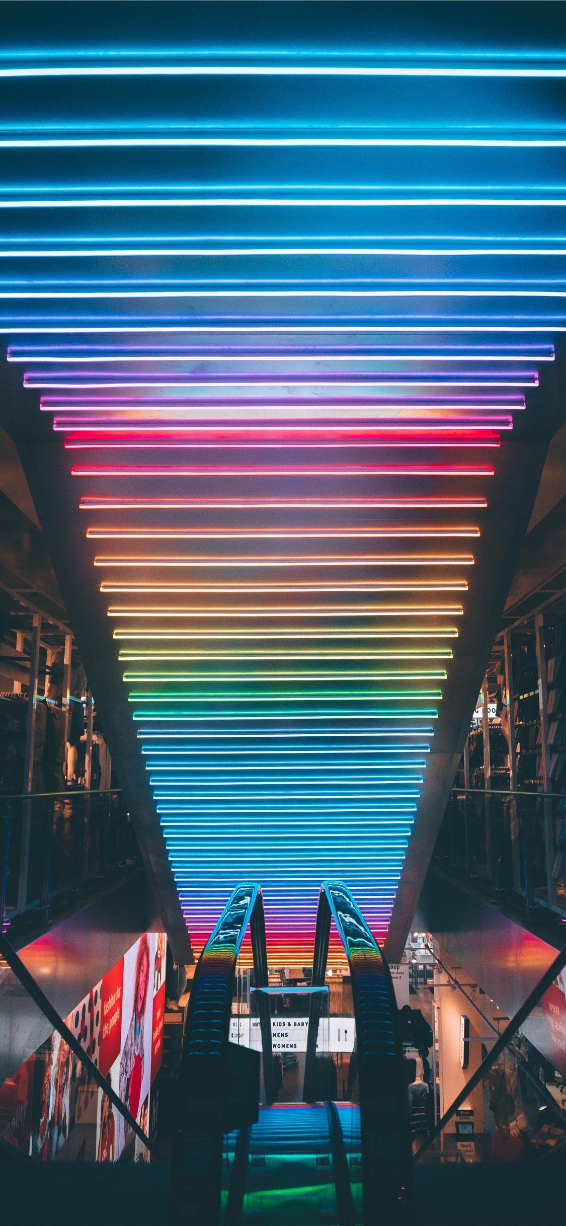 A long escalator with a rainbow of lights above it - Architecture