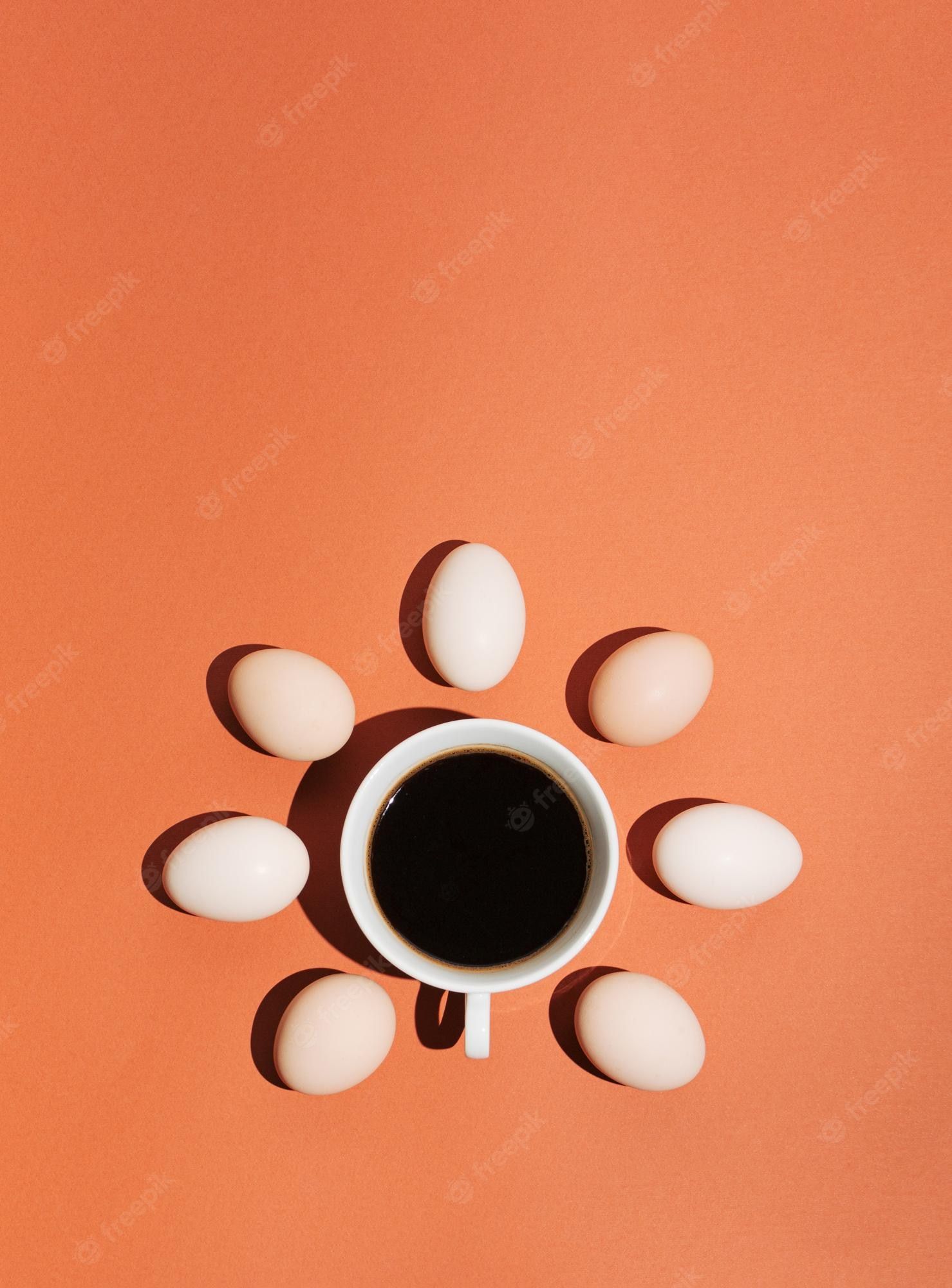 A cup of coffee surrounded by eggs on an orange background - Coffee