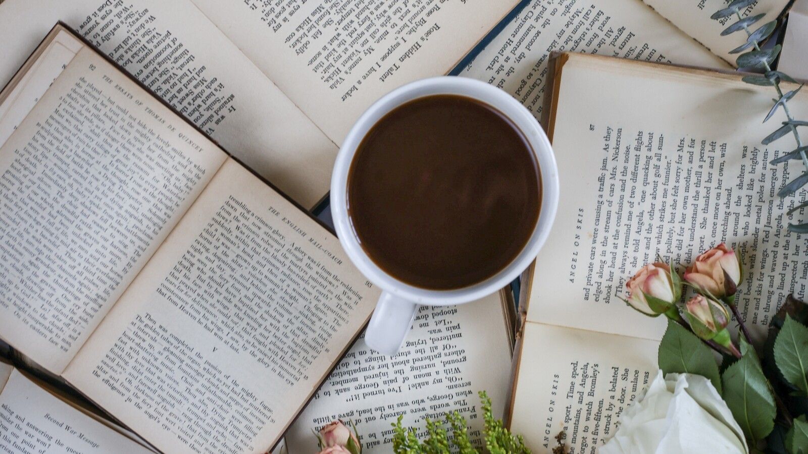 A cup of coffee sitting on top of a pile of books. - Coffee