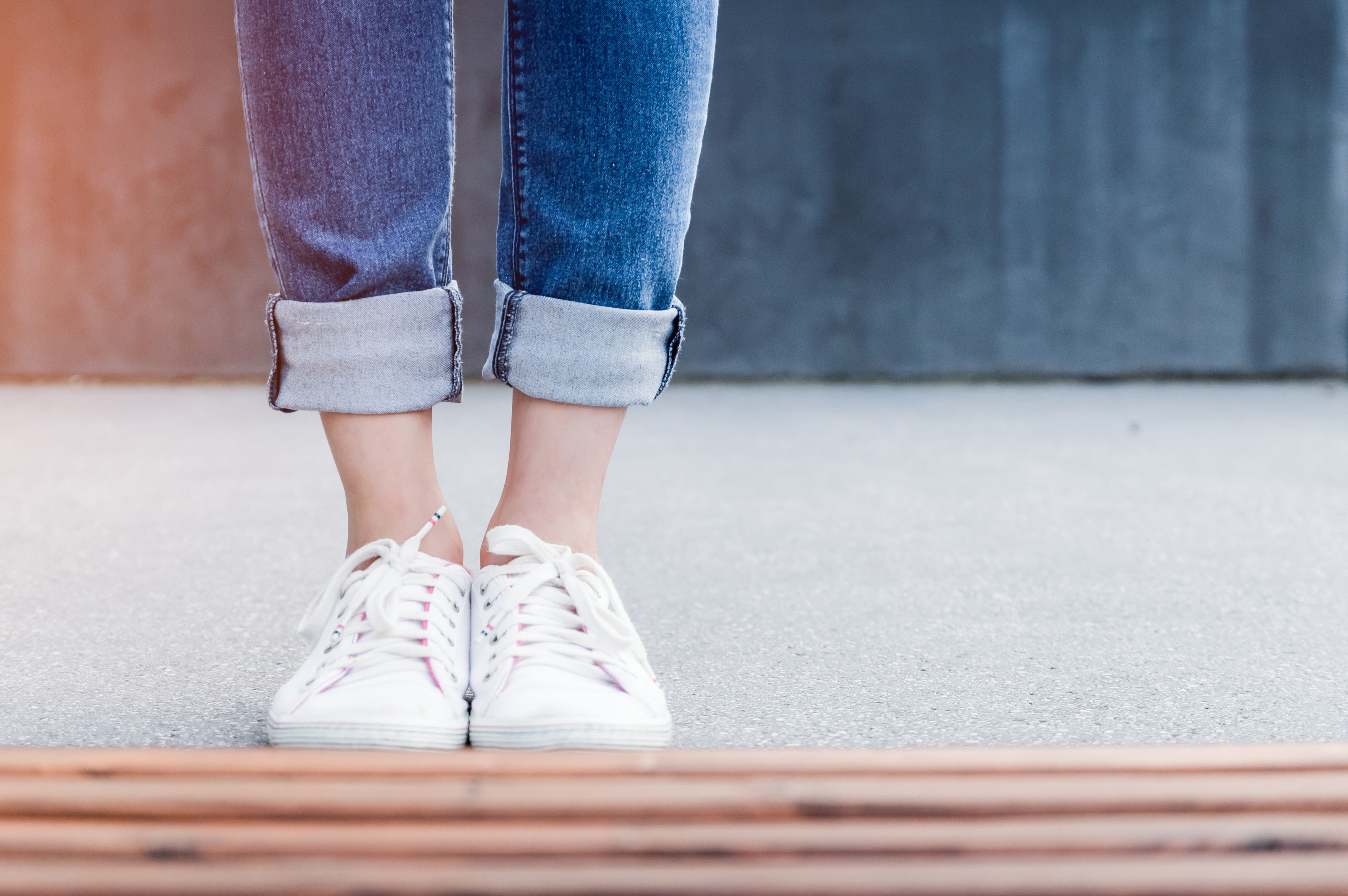 A person standing on the sidewalk with their feet in white shoes - Shoes