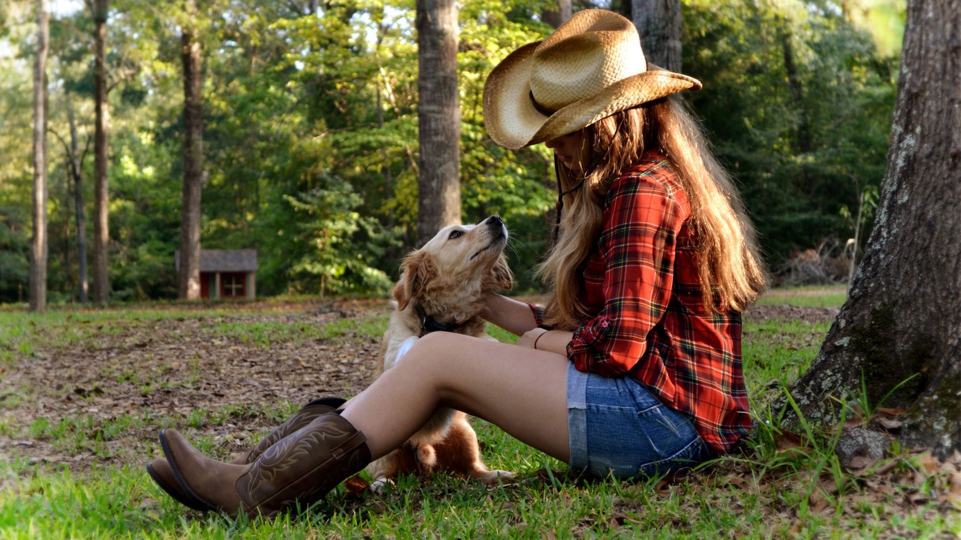 A woman in cowboy hat and boots petting her dog - Cowgirl