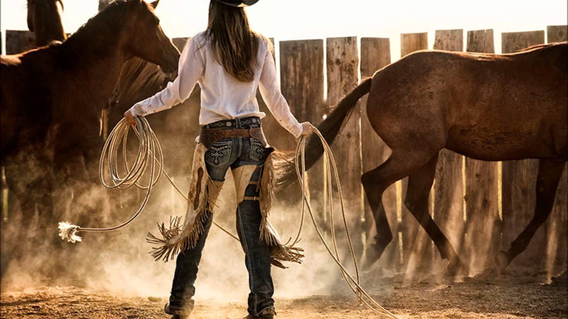 A woman in cowboy boots and jeans is holding ropes for horses - Cowgirl