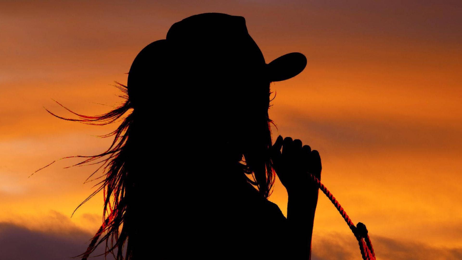 A woman in cowboy hat holding her horse - Cowgirl