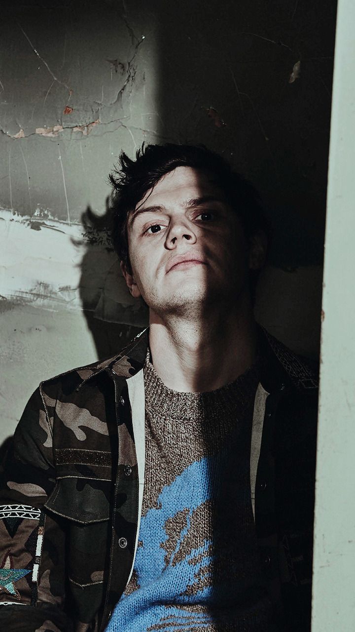 A man in a camo jacket and blue sweater - Evan Peters