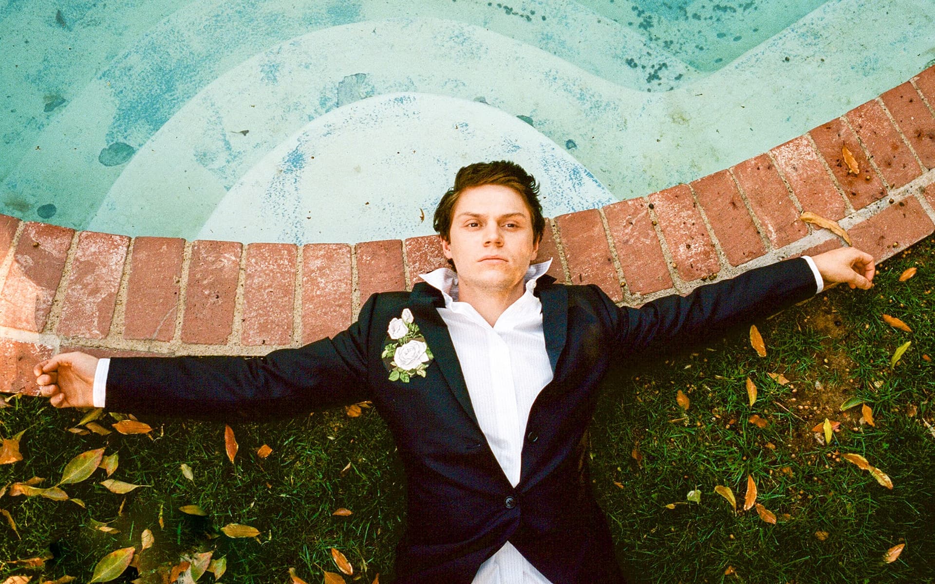 A man laying on the ground with his arms out - Evan Peters