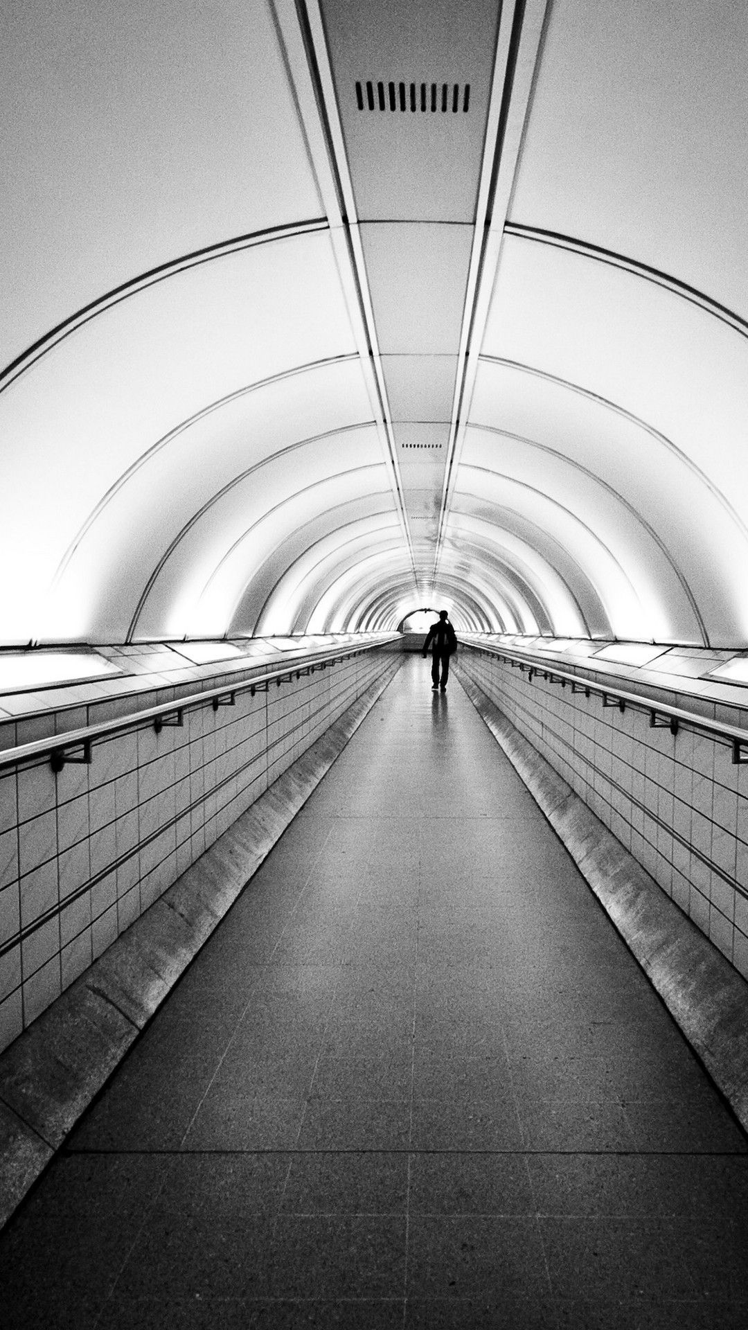A person walking down an empty tunnel - Gray