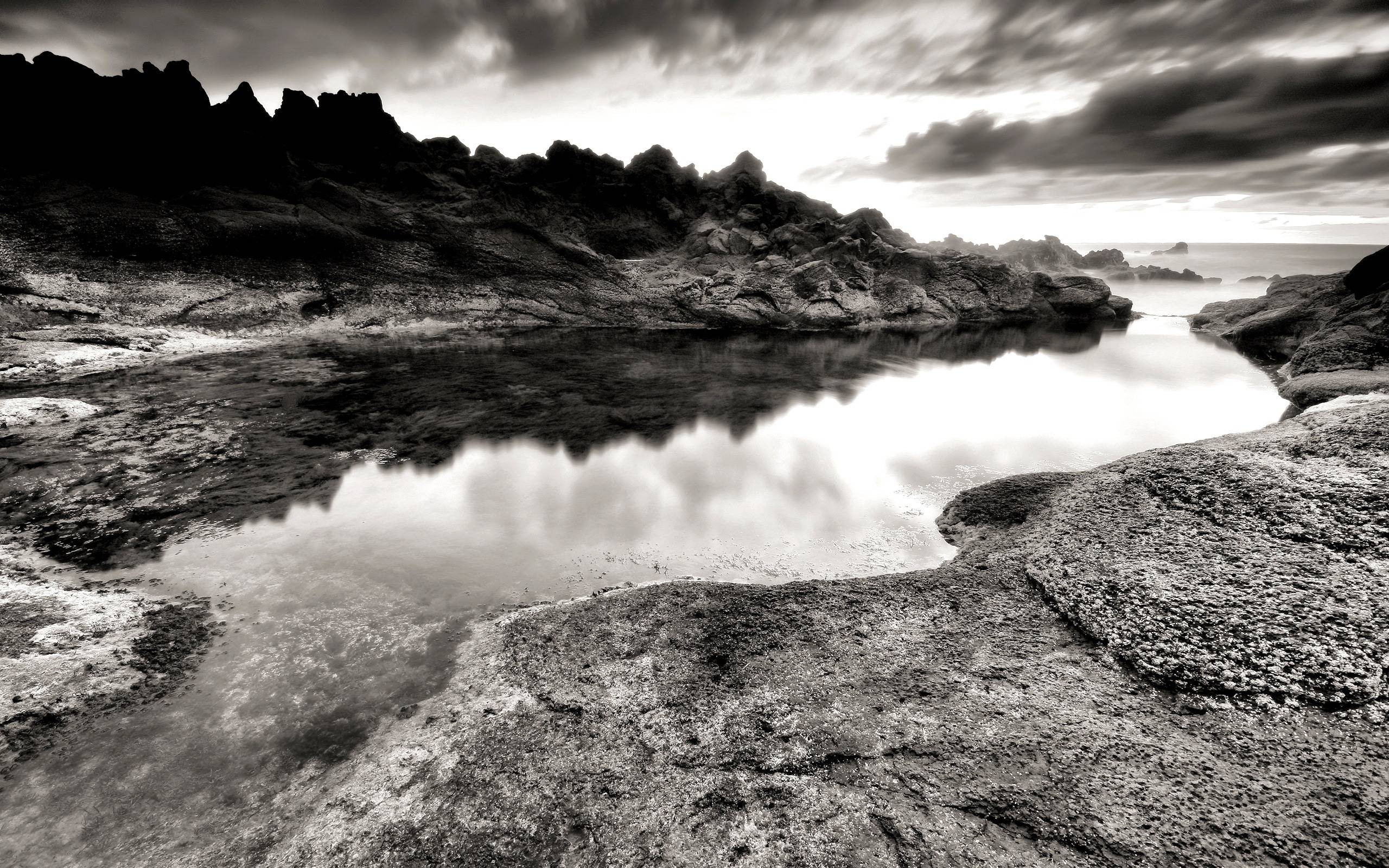 A black and white photo of rocks on the beach - Black and white, gray, lake