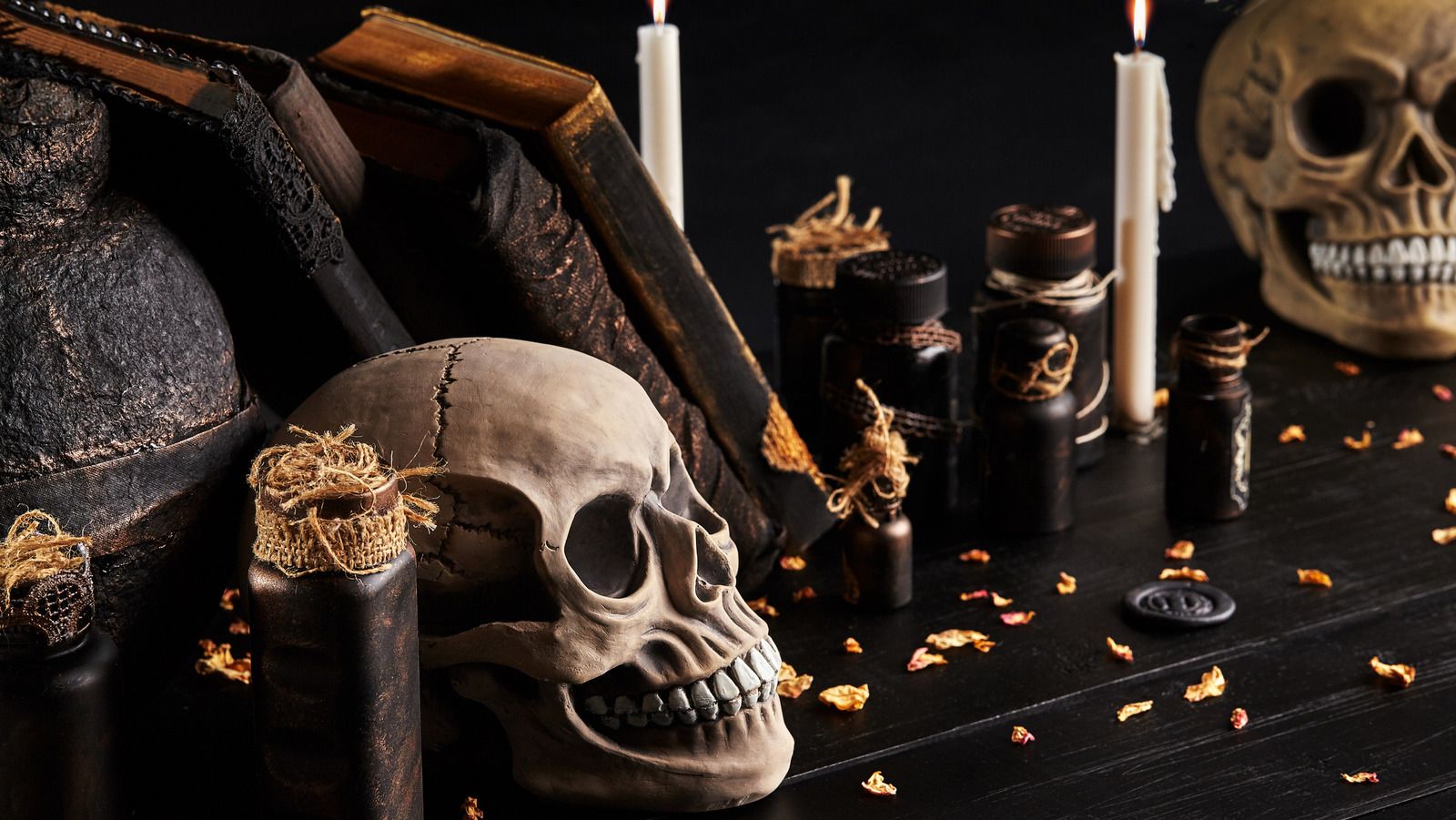 A skull, a book, and some candles on a table. - Dark academia