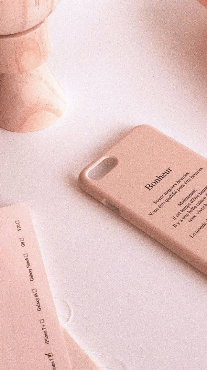 A pink iphone case sitting on top of some paper - Peach