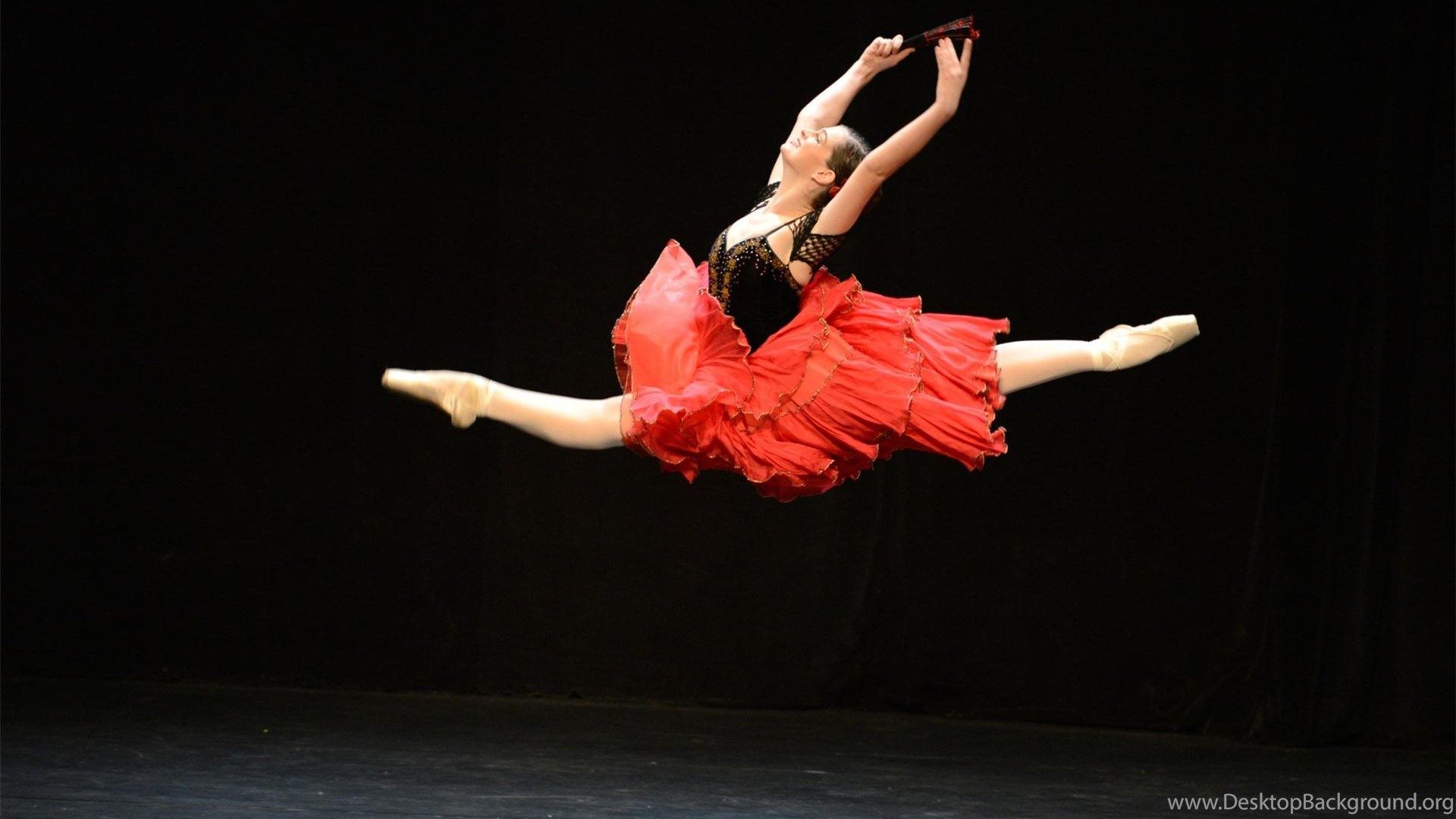 A ballerina in a red dress leaps into the air. - Dance