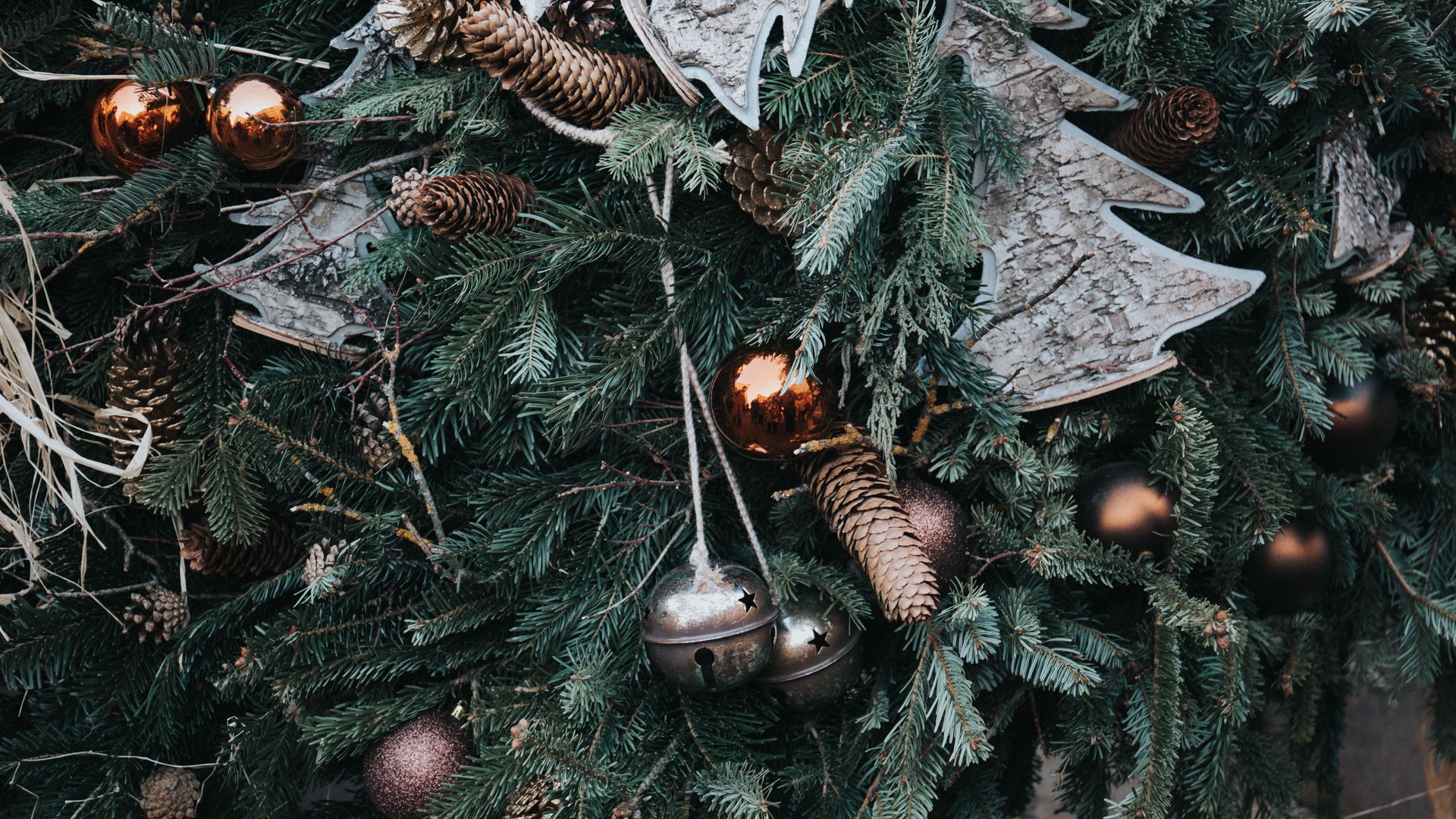 A close up of a Christmas tree with ornaments and pinecones. - New Year