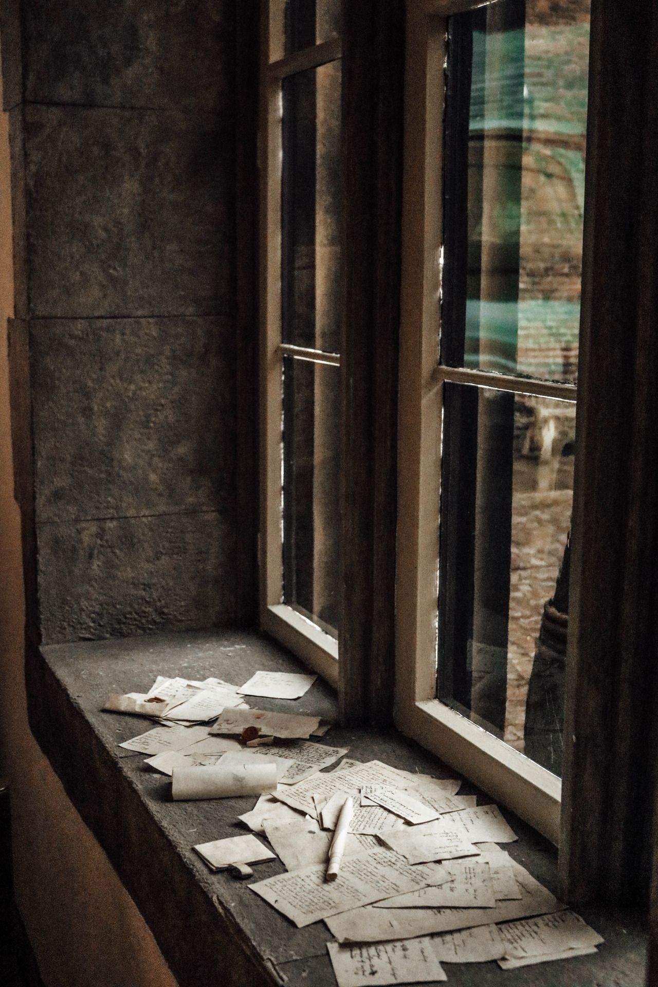 Sheets of paper are scattered on a windowsill. - Dark academia