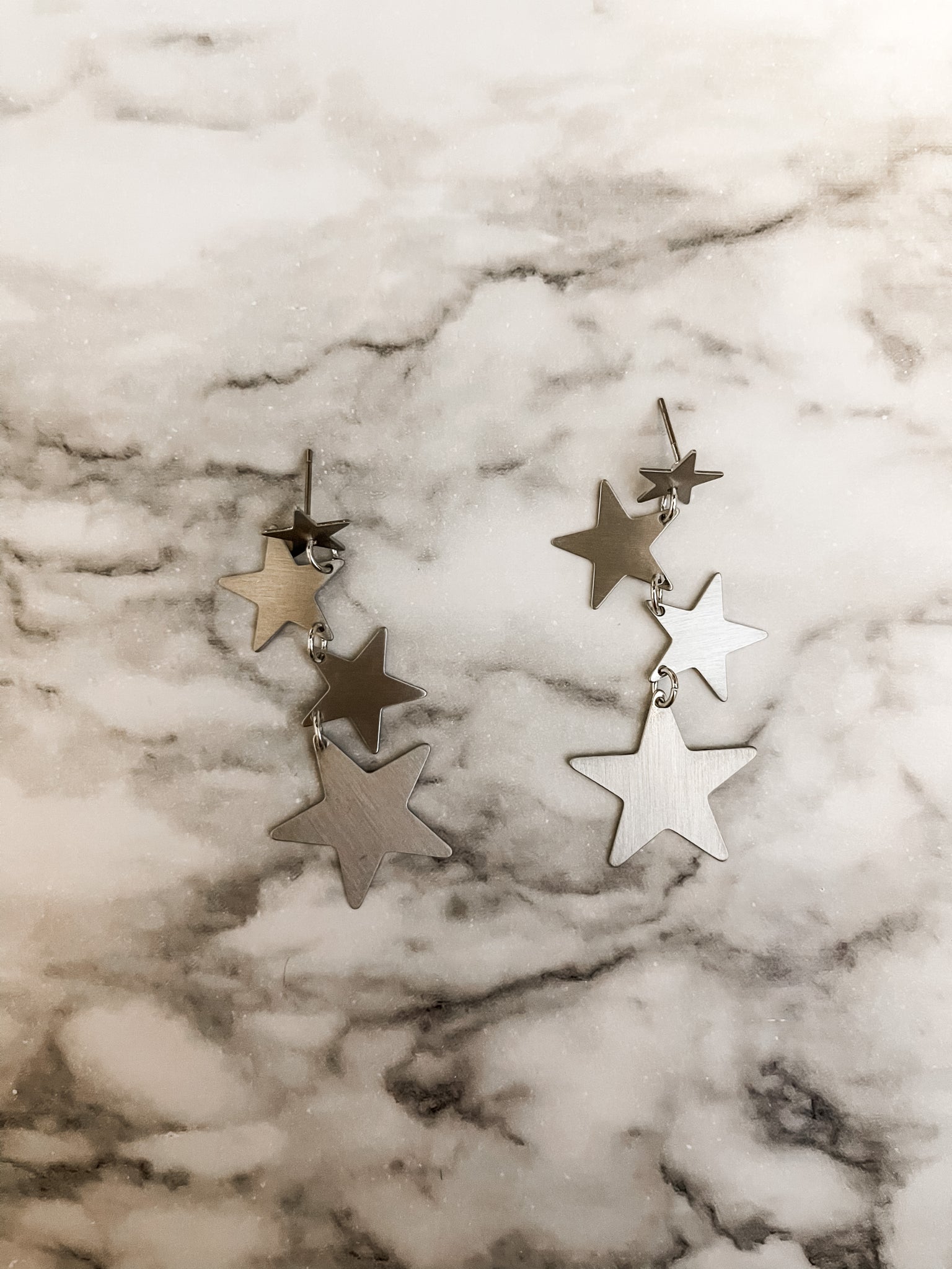 A pair of silver star earrings on top - Silver
