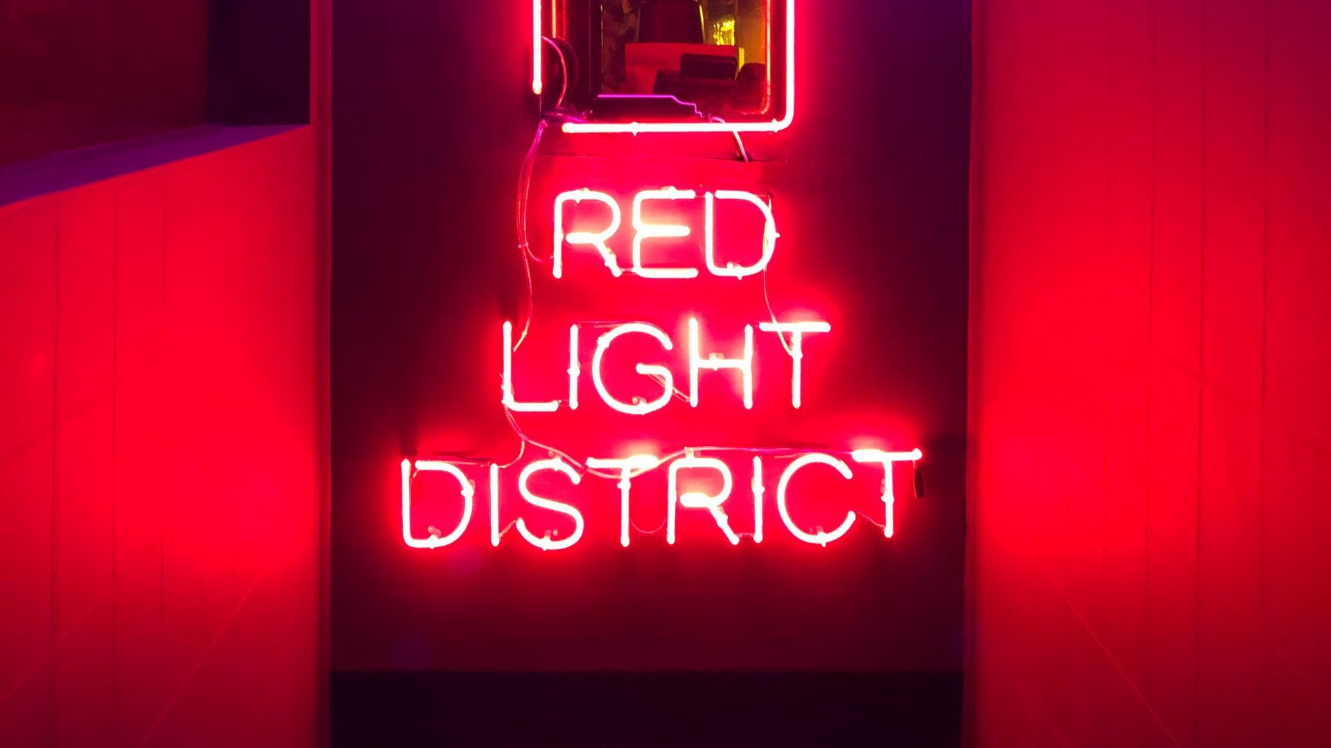 A neon sign that says red light district - Neon red