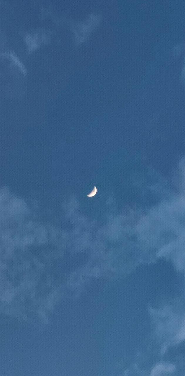 A crescent moon in a blue sky with some clouds. - Moon