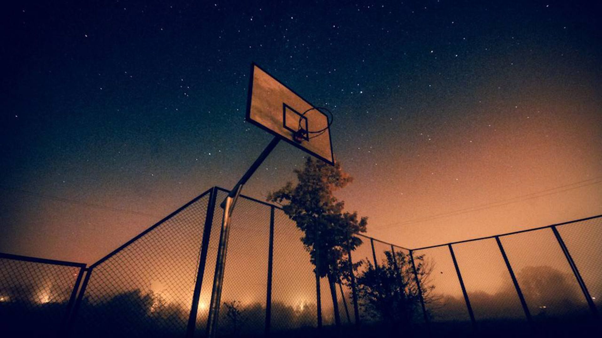 A basketball hoop at night with a starry sky in the background. - Basketball