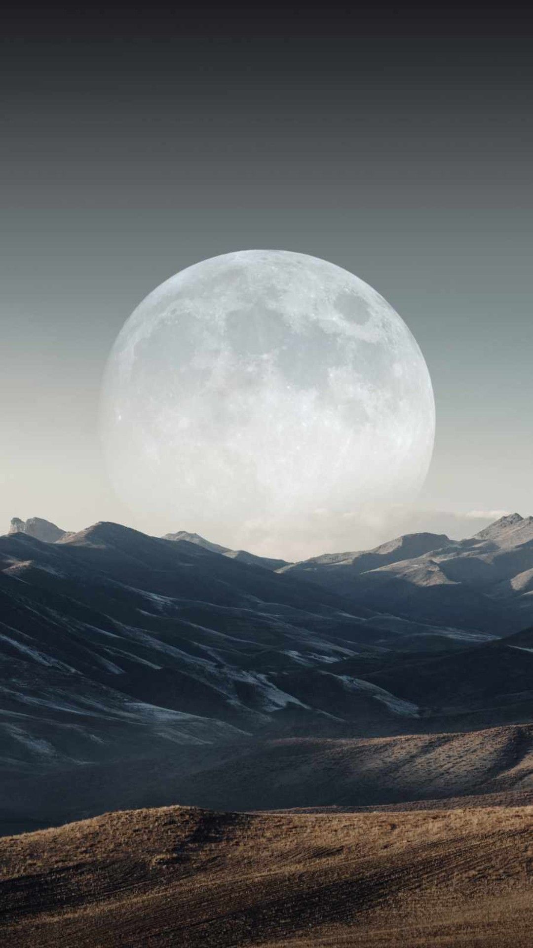 IPhone wallpaper of a full moon rising over a mountain range - Moon