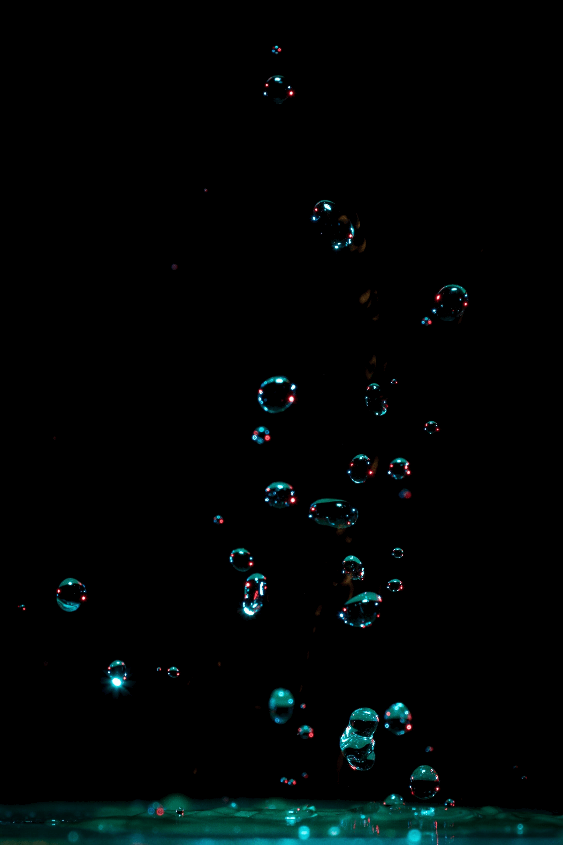 Water droplets splash in the air, creating a beautiful pattern against a black background. - Water