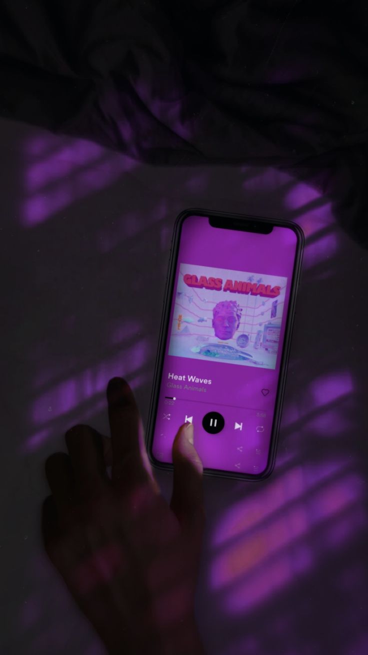 A phone with the album cover of Heat Waves by Glass Animals on the screen. - Wave