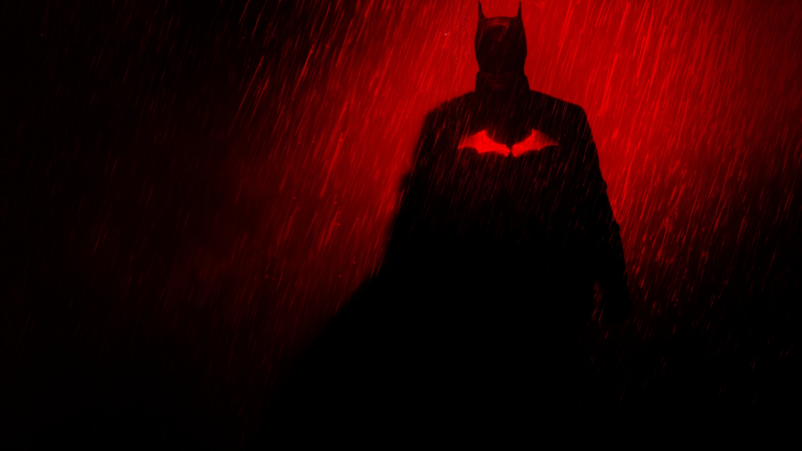 Batman standing in the rain with a red spotlight behind him. - Batman