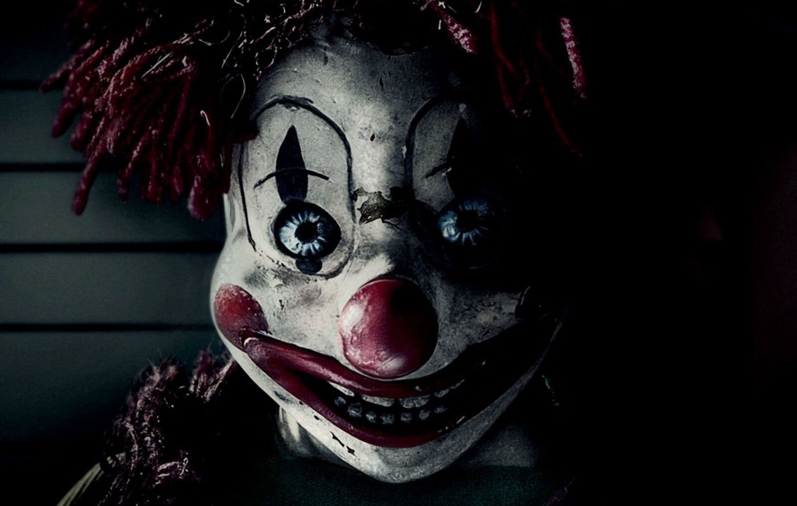 A scary clown doll with one blue eye and one red eye, smiling. - Clown