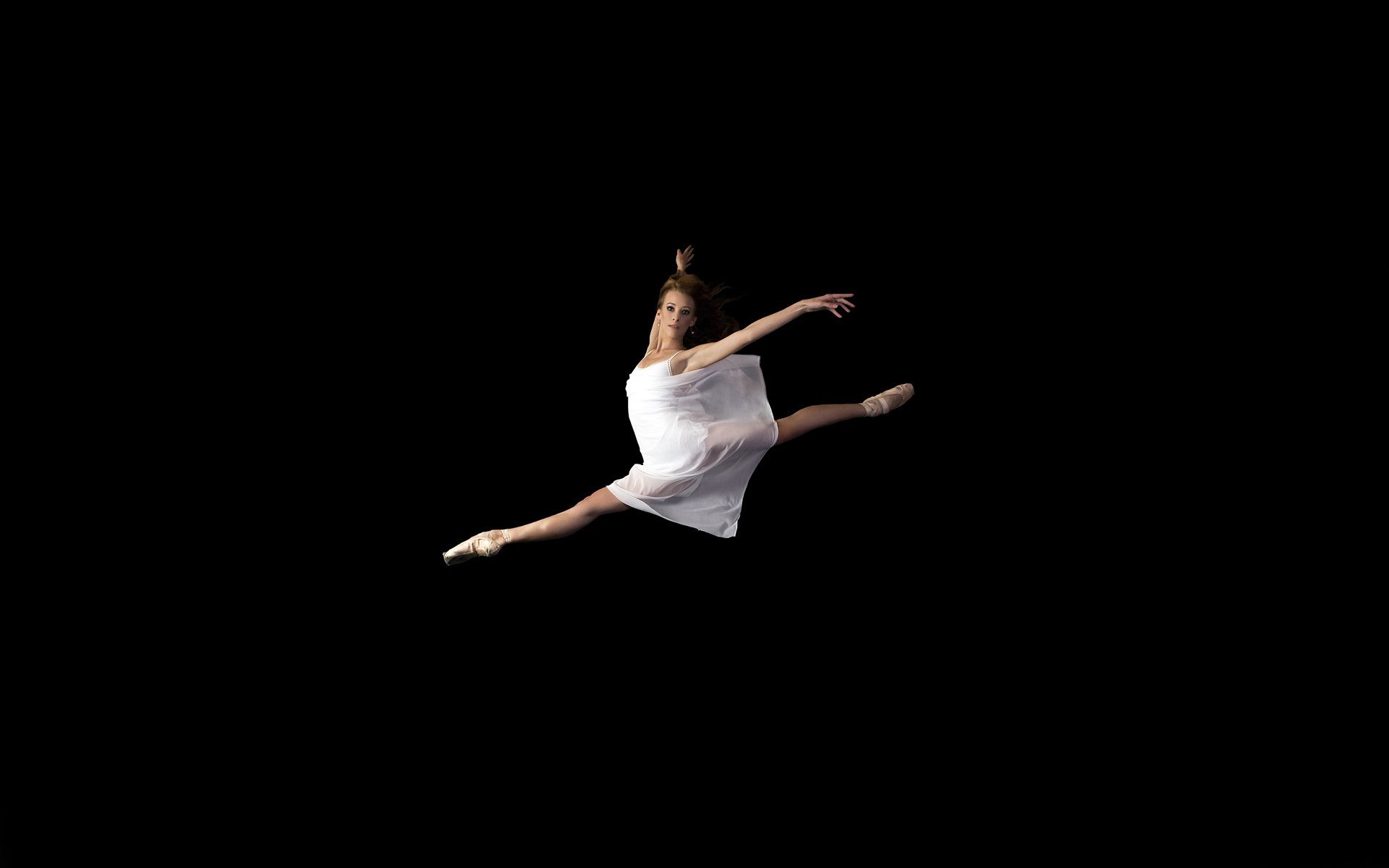 A ballerina in a white dress leaps into the air with her arms outstretched. - Ballet