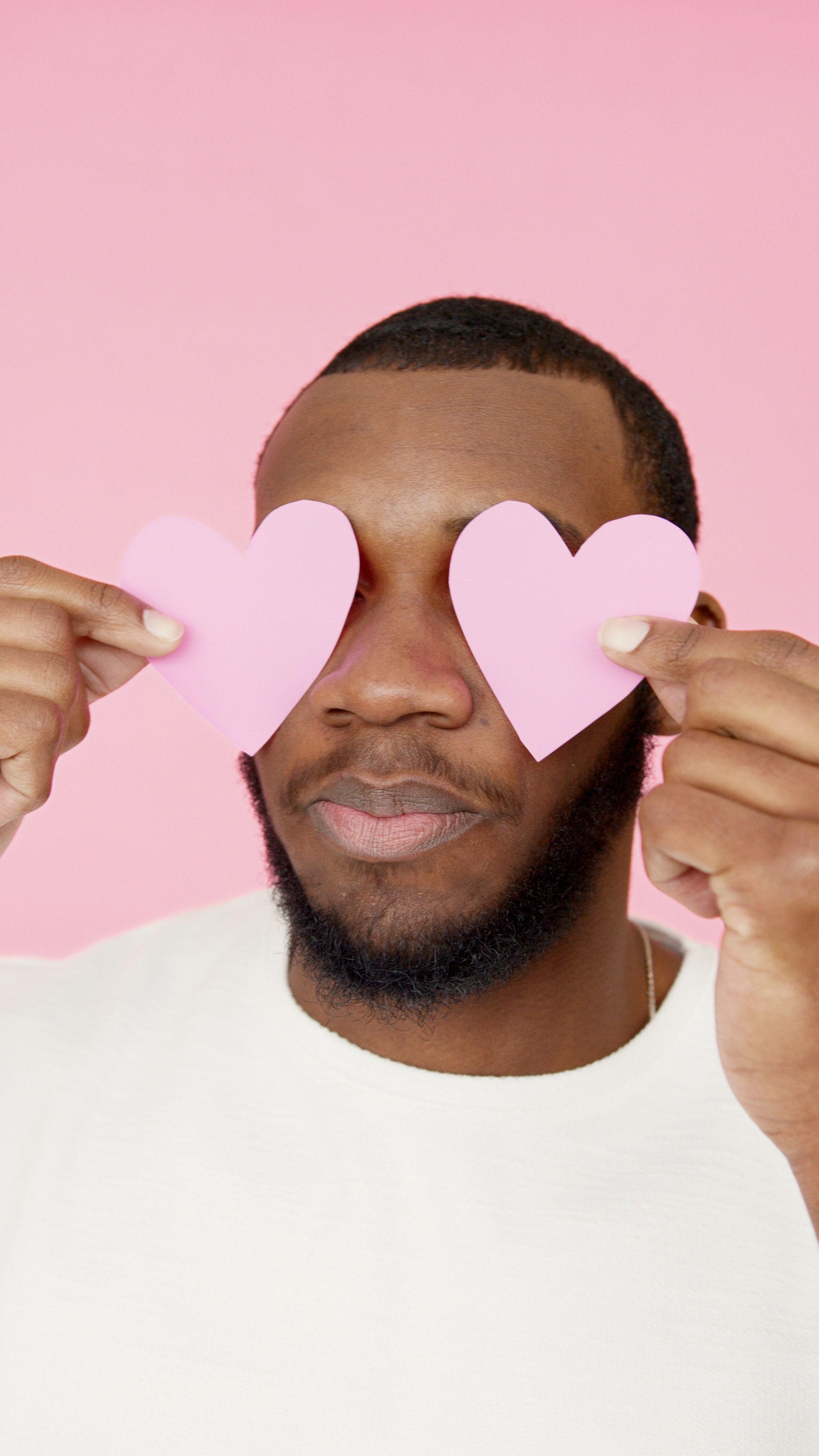 A man is holding up pink hearts in front of his face - Drake