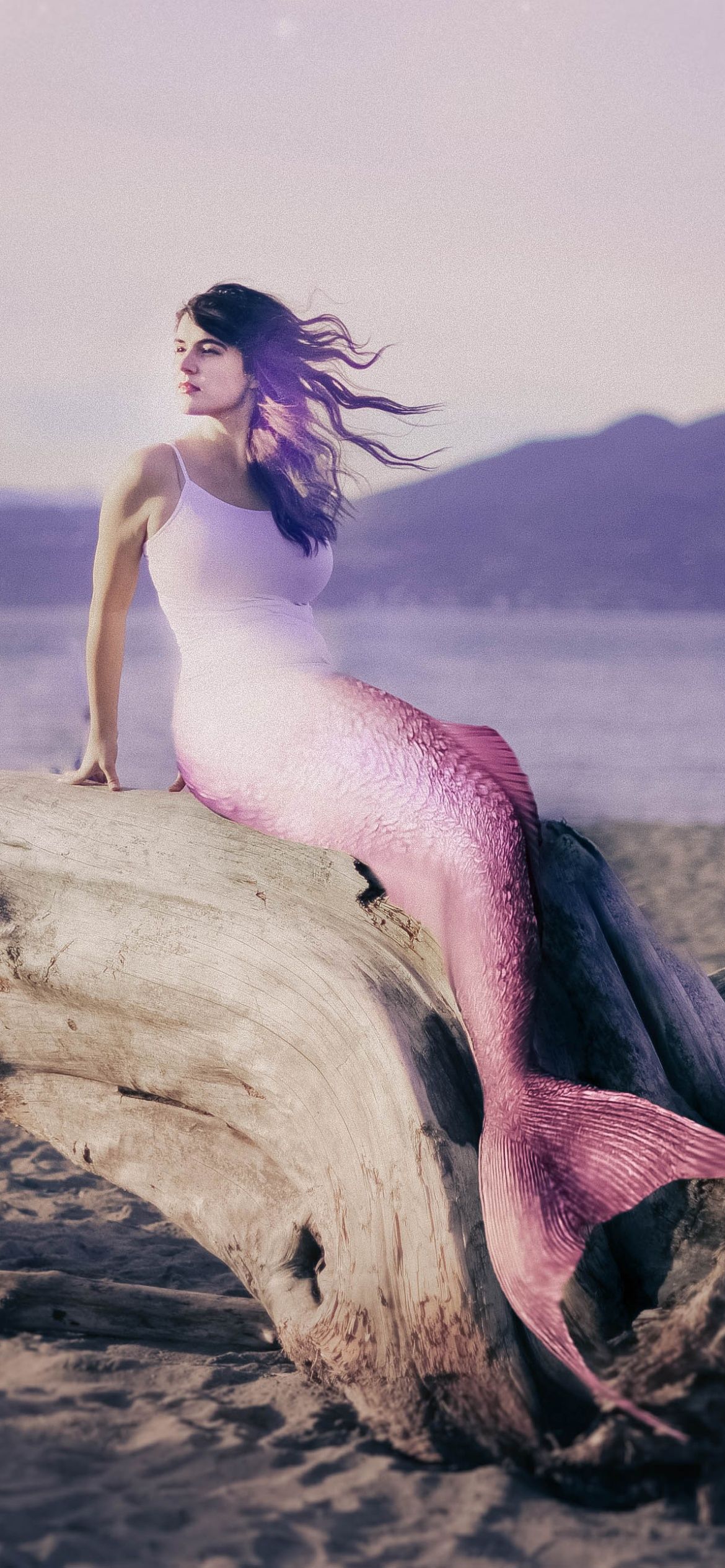 A woman sitting on top of an old log - Mermaid