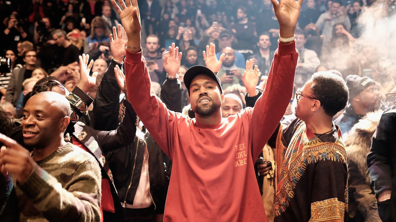 Kanye West raises his hands in the air during a performance - Kanye West