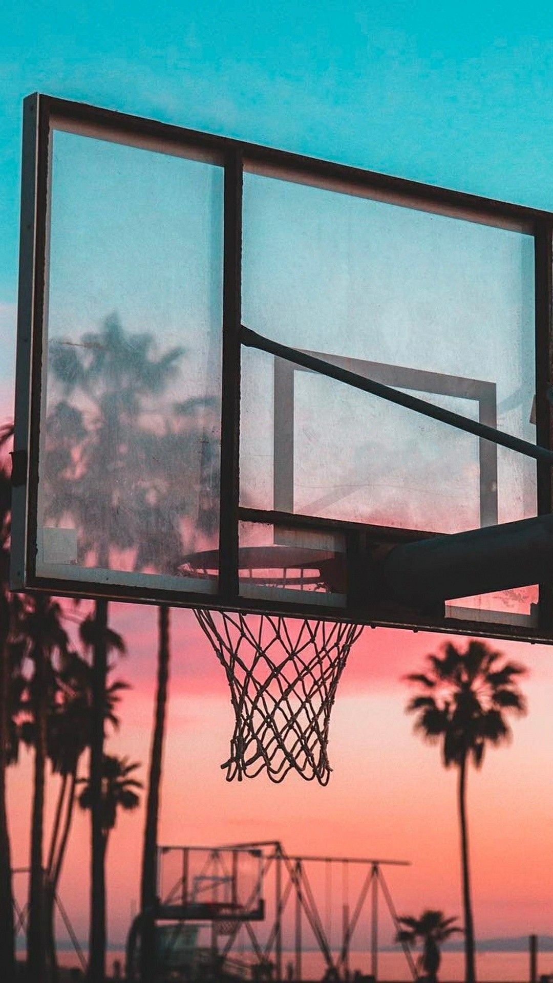 A basketball hoop with the sun setting in front of it - Basketball