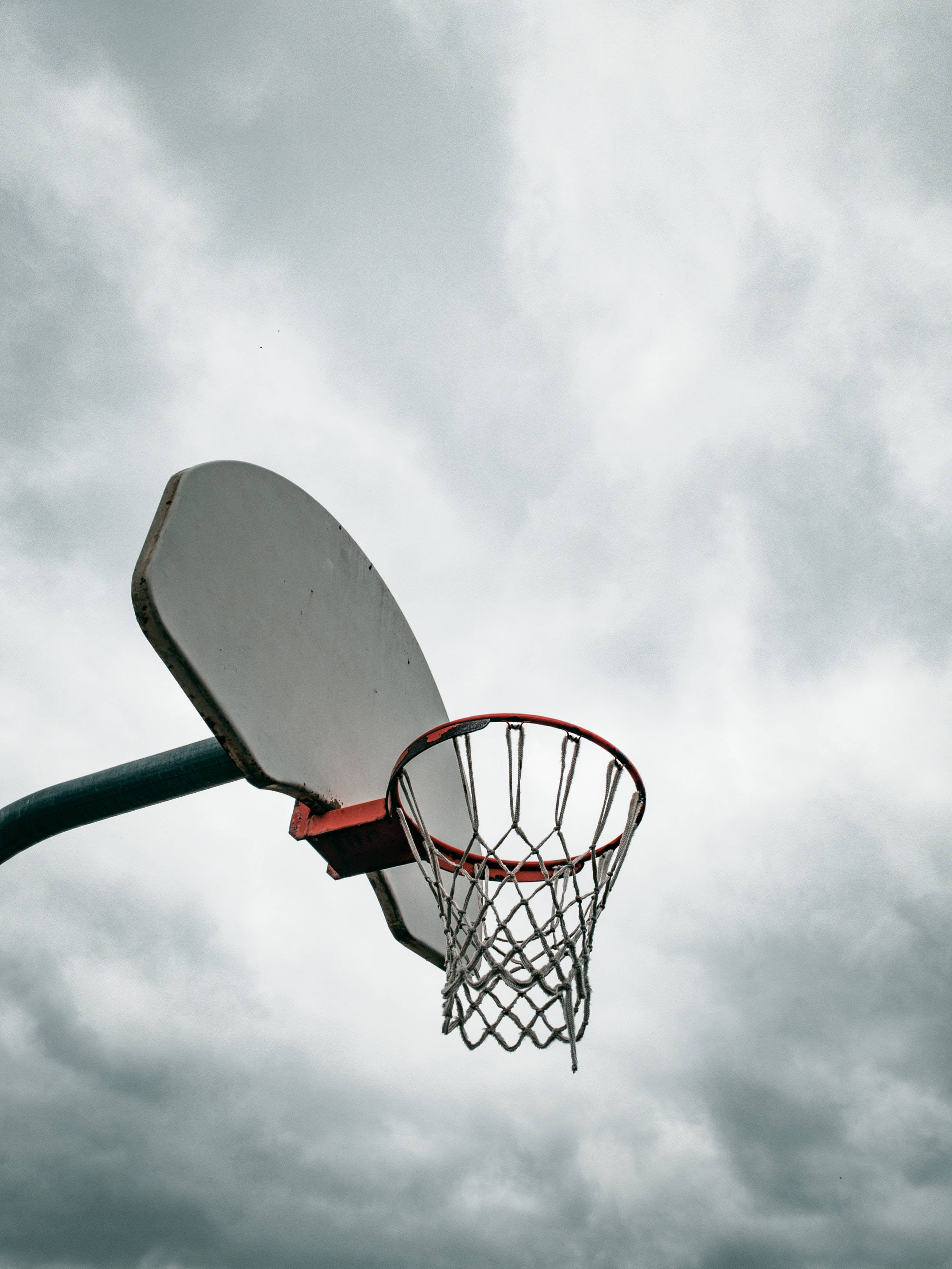 A basketball hoop with a cloudy sky in the background. - Basketball