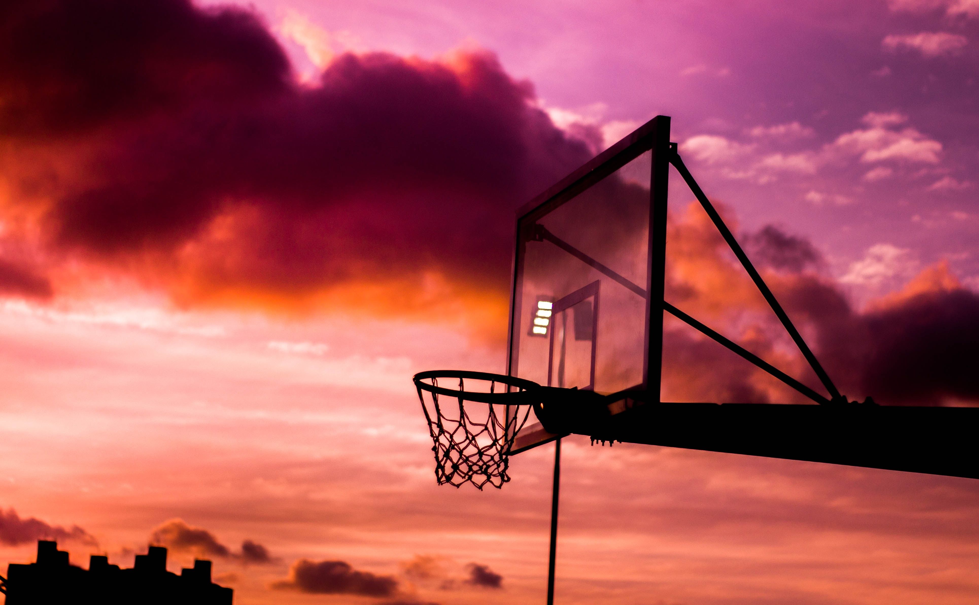 A basketball hoop with a purple and orange sunset in the background. - Basketball