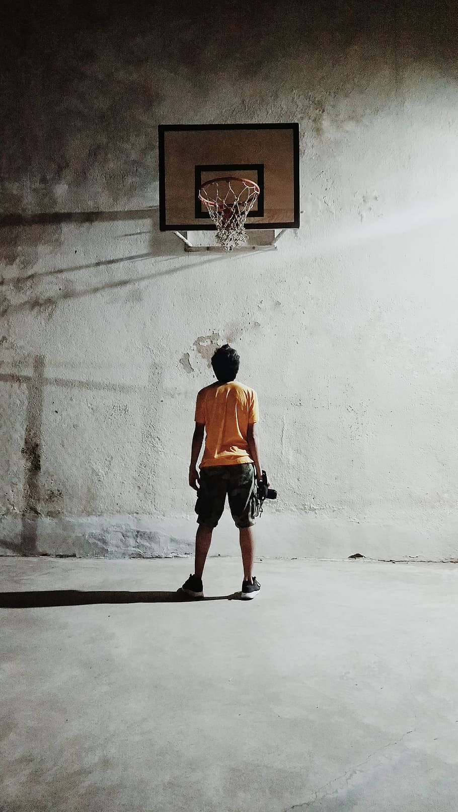A man standing underneath an empty basketball hoop - Basketball