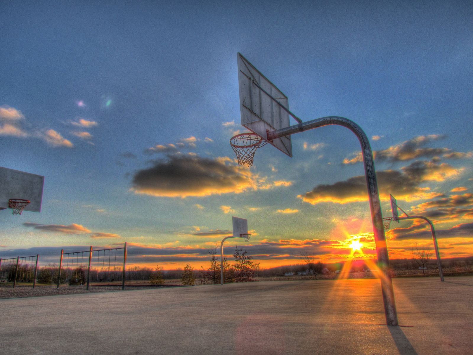 A basketball hoop with the sun setting in the background. - Basketball