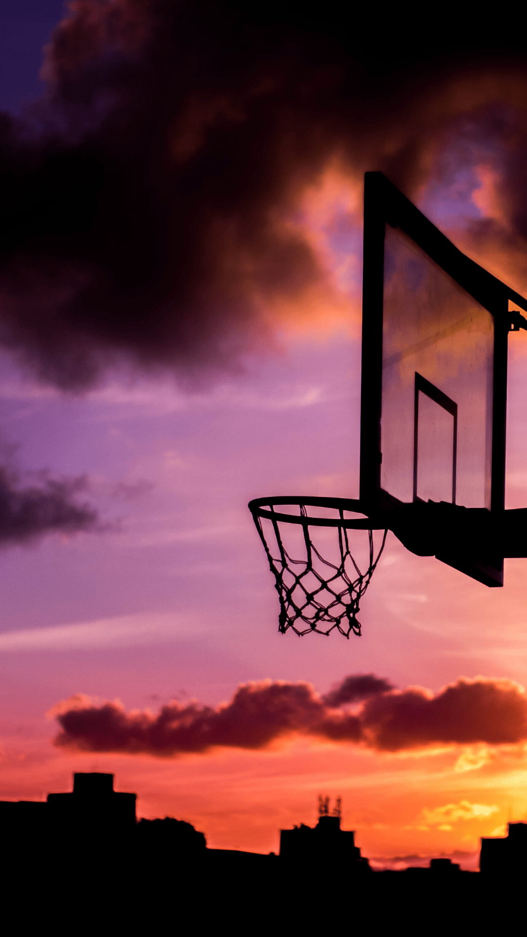 A basketball hoop with a purple and orange sunset in the background. - Basketball