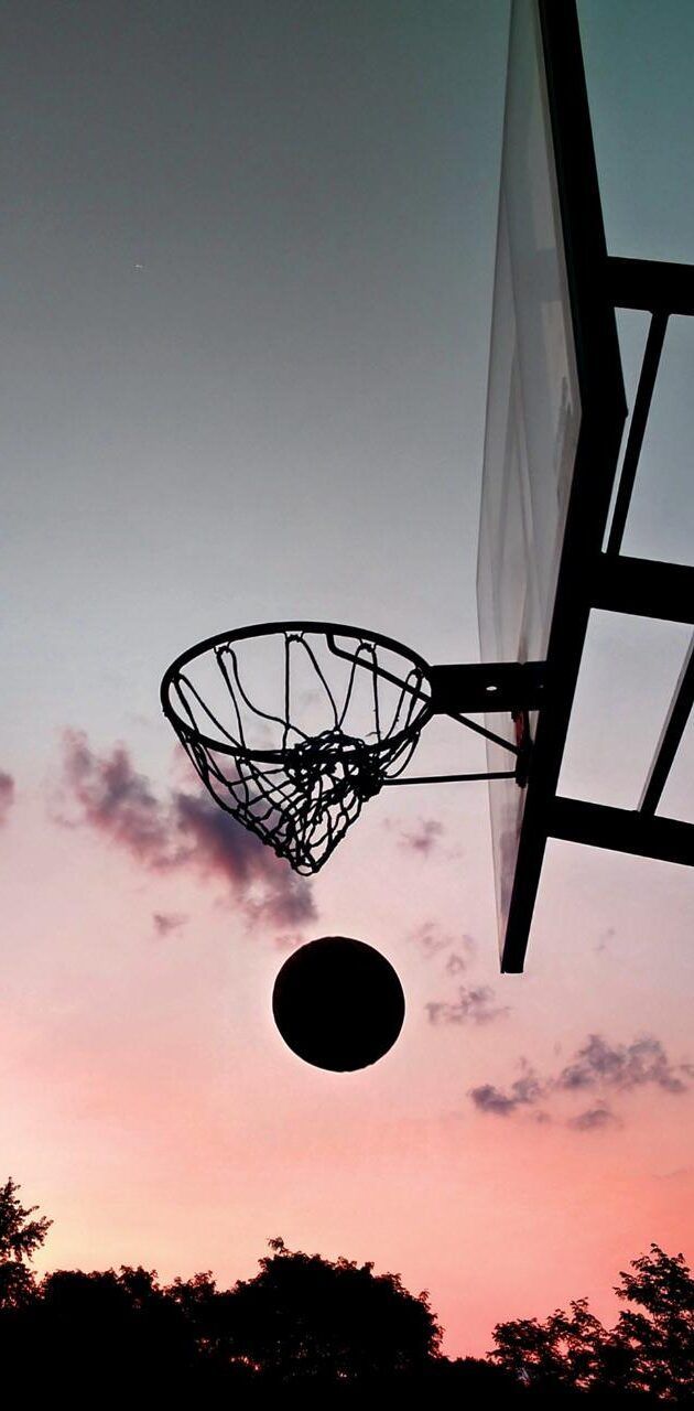 A basketball flying through the air with a basketball hoop in the background. - Basketball