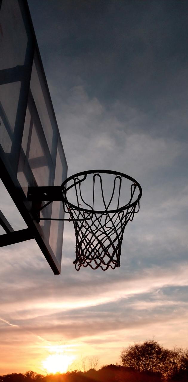 A basketball hoop with the sun setting in the background - Basketball