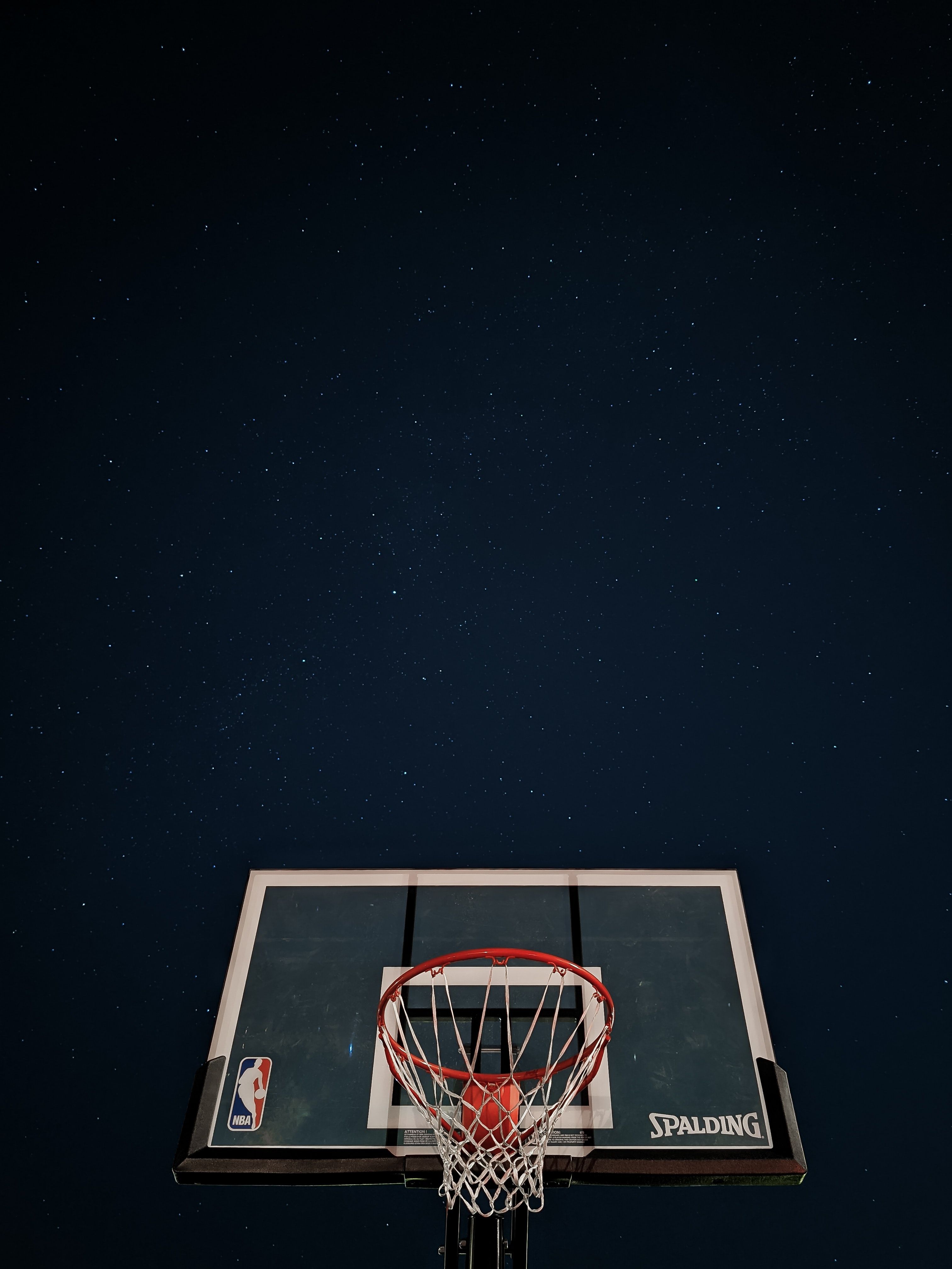 A basketball backboard with a basketball in the hoop. - Basketball