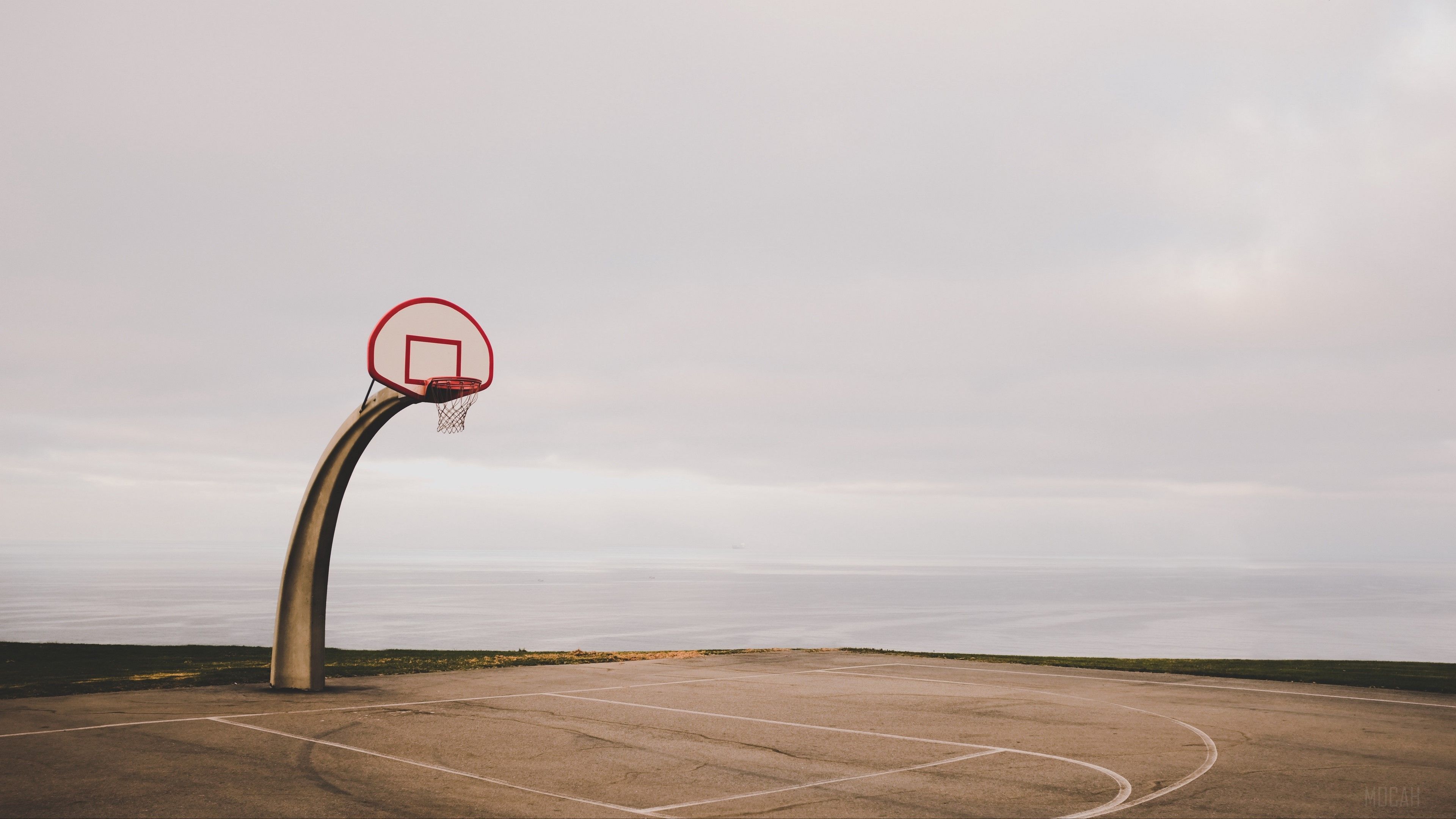 A basketball hoop is on the side of an empty parking lot - Basketball