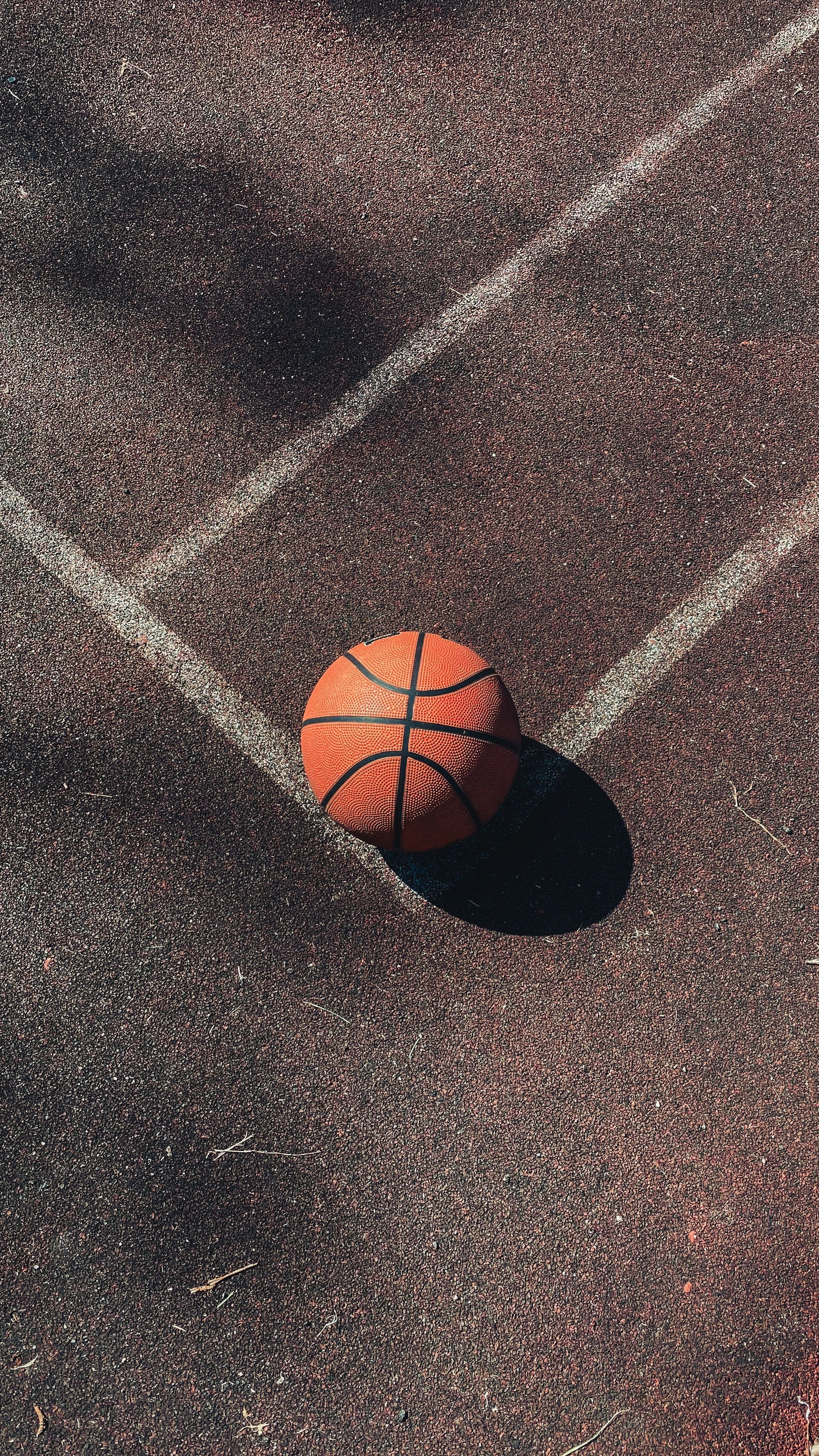 A basketball sits on the court, waiting for a game to start. - Basketball